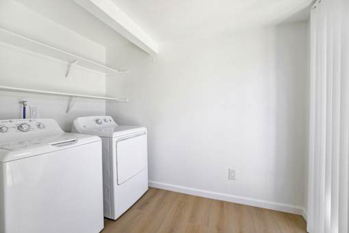 Laundry room with white washer and dryer at Coventry Square Apartments, Upland, California