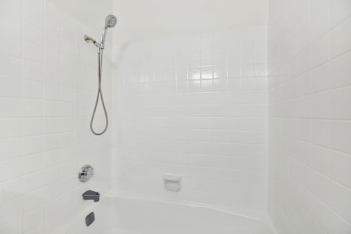 Bathtub with handheld shower and tile surround at Coventry Square Apartments, California, 97186