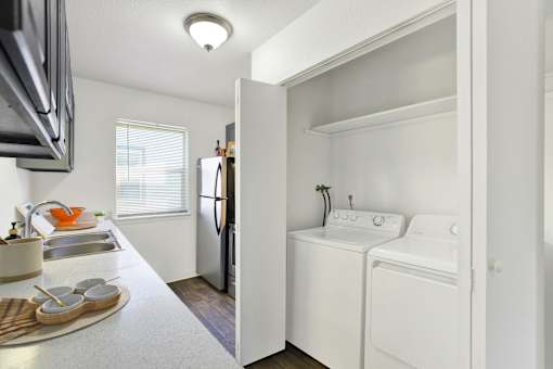 A small kitchen with a refrigerator, washer and dryer.