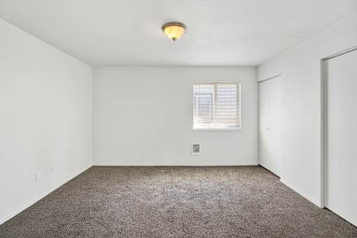 A room with a carpeted floor and a window with blinds.