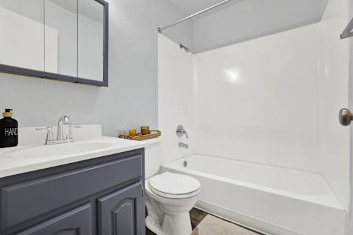 A white toilet sits next to a white bathtub in a bathroom.