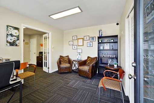 A room with a couch, chairs, and pictures on the wall.