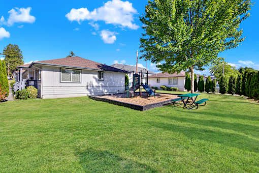 A house with a green lawn and a tree in front.