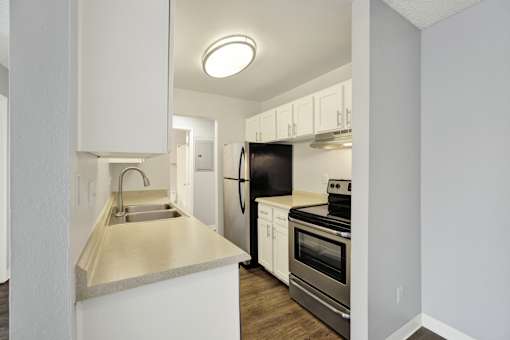 A kitchen with white cabinets and a black refrigerator.