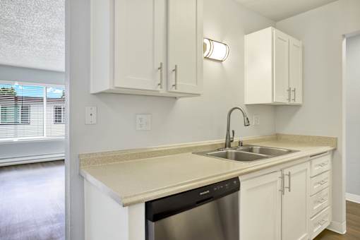A kitchen with white cabinets and a beige countertop.