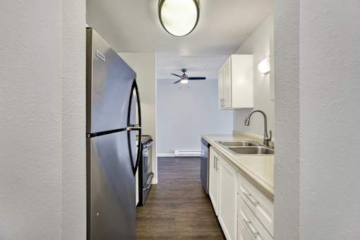 A kitchen with a stainless steel refrigerator and white cabinets.