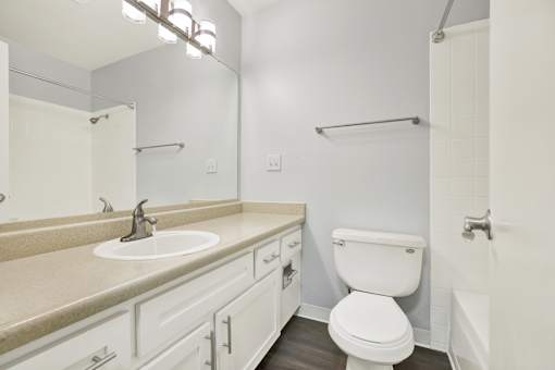 A white toilet is in a bathroom with a sink and mirror.