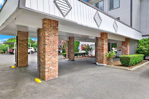 A parking lot with a building entrance supported by pillars.