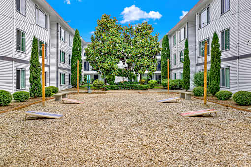 A courtyard with a gravel surface and a tree in the middle.
