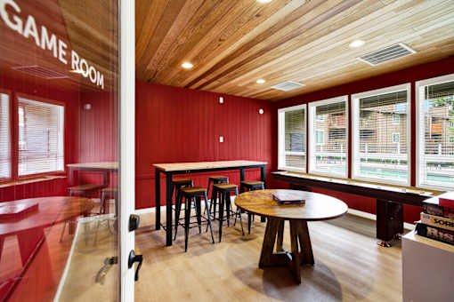 A room with a wooden ceiling and a table with stools.