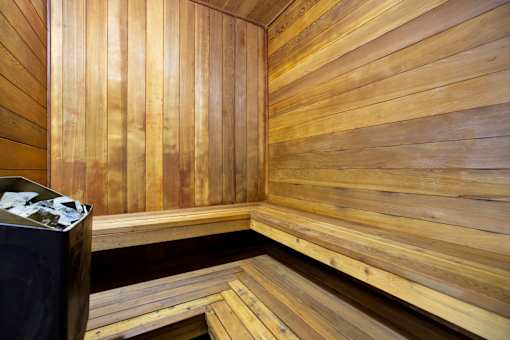 A wooden sauna with benches and a container of stones.