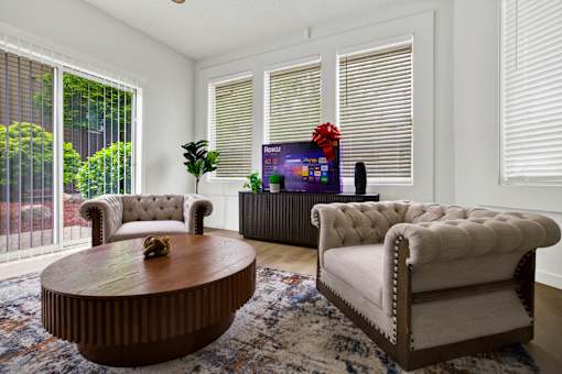 A living room with a brown coffee table and two white chairs.