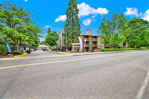 A road with a building on the right side and trees on the left.