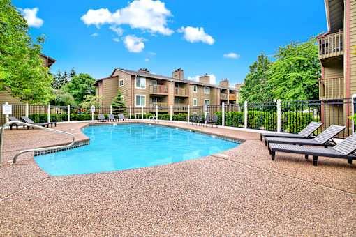 A pool surrounded by a fence and chairs.