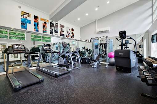 A gym with a variety of equipment including treadmills, exercise bikes, and weights.