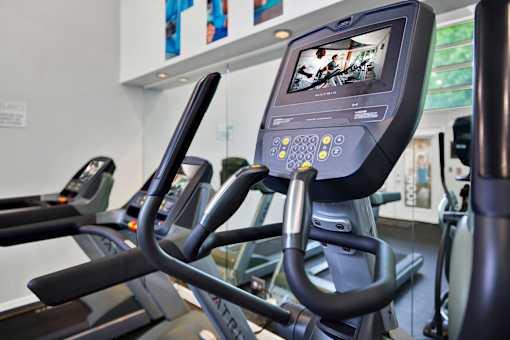 A row of treadmills in a gym with a monitor on the front.