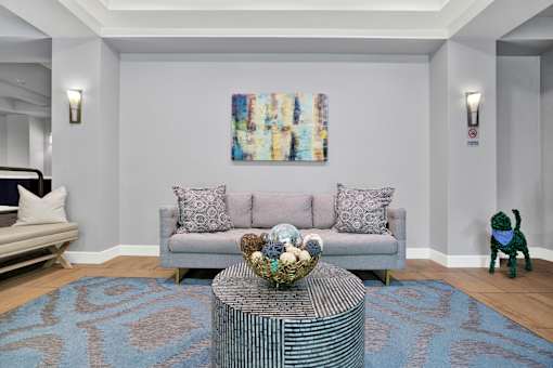 A living room with a grey couch, a coffee table, and a painting on the wall.