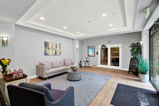 A living room with a couch, chairs, and a painting on the wall.