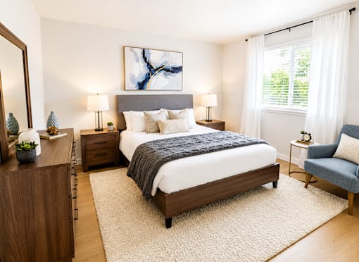 A bedroom with a large bed, a nightstand, a chair, and a painting on the wall.