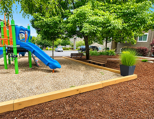A playground with a blue slide and a green climbing frame.
