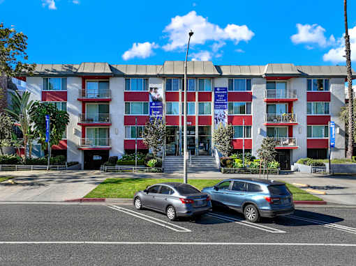 Two cars are parked in a parking lot in front of a red and white building. at Chateau La Fayette, California