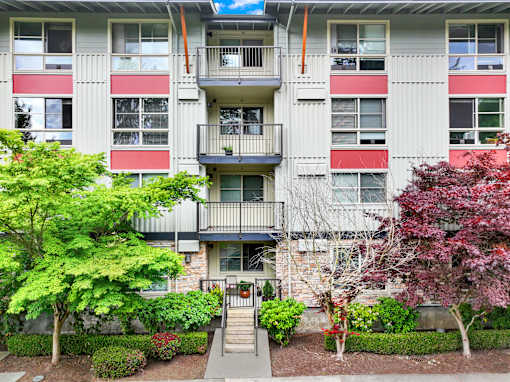 A building with a balcony and a small garden in front.