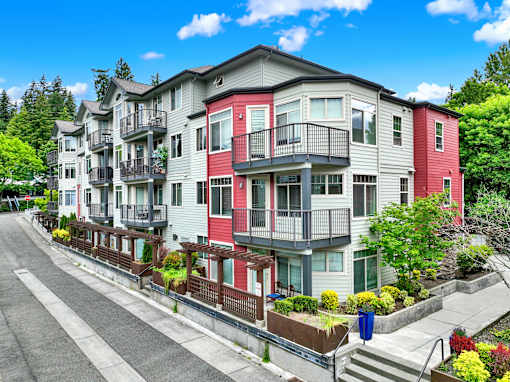 A row of multi-story apartment buildings with balconies and flower pots on the steps.