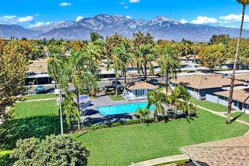 Aerial view of pool area with palm trees and mountains at Coventry Square Apartments, Upland, CA 97186