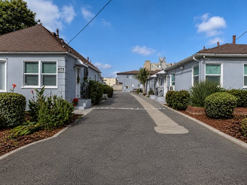 A residential street with houses on both sides and a clear blue sky.