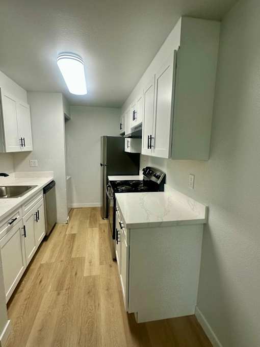 A kitchen with white cabinets and a black fridge.