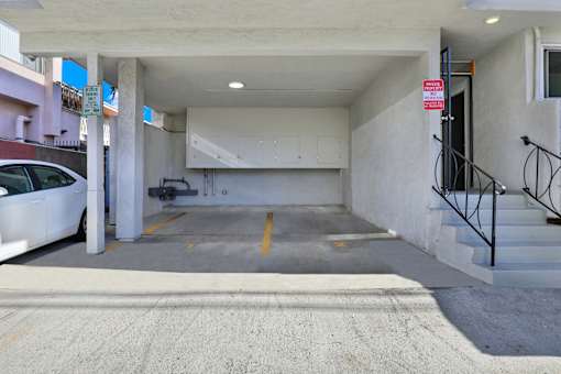 A parking garage with a white car parked on the left side.at Federal Apartments, Los Angeles