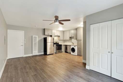 A kitchen with a white ceiling fan and wooden floors.at Federal Apartments, California