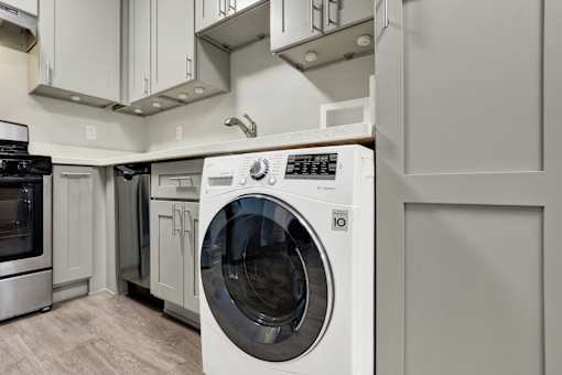 A white front load washing machine in a modern kitchen.at Federal Apartments, Los Angeles California