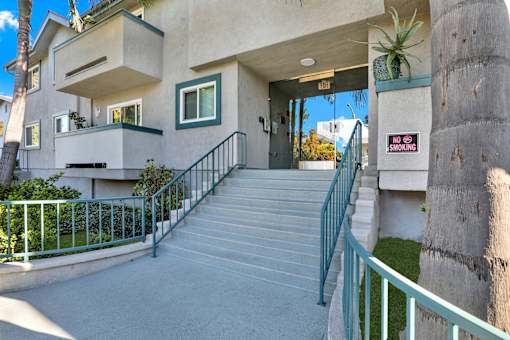 A concrete staircase with a green railing leading to a building entrance. at Elmwood Gardens, Burbank, California