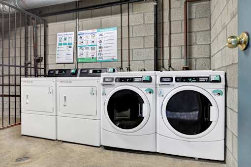 Three front loading washing machines are lined up in a laundry room. at Elmwood Gardens, California, 91502