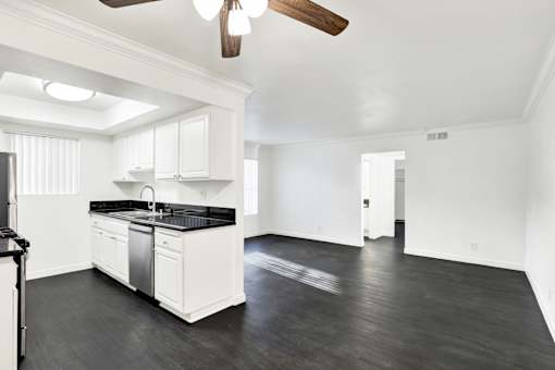 A spacious kitchen with white cabinets and black countertops. at Elmwood Gardens, California, 91502