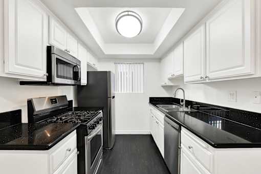 A black and white kitchen with white cabinets. at Elmwood Gardens, Burbank, California