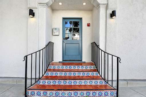 A staircase with a blue door and black railings.at Barton Apartments, California