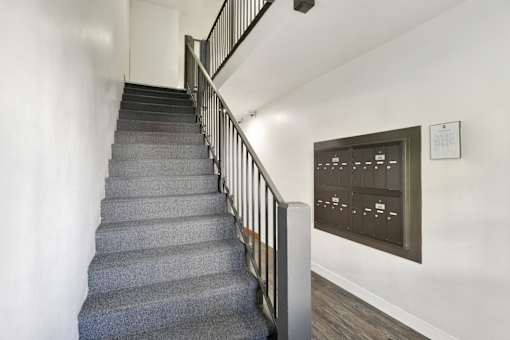A staircase with a grey carpeted runner and a metal railing.at Barton Apartments, Los Angeles, CA