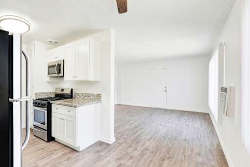 A kitchen with white cabinets and a black refrigerator at Sylvan Gardens,Van Nuys,California