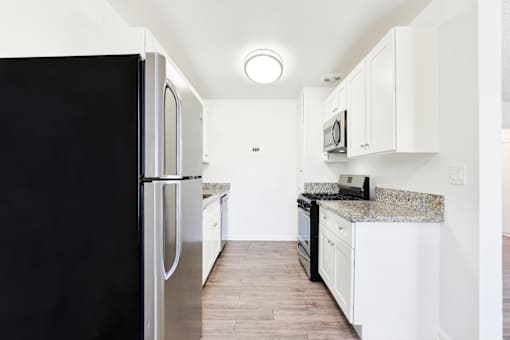 A black refrigerator is on the left in a white kitchen at Sylvan Gardens,Van Nuys,CA,91401