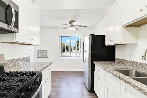A kitchen with black appliances and white cabinets at Sylvan Gardens,Van Nuys,91401