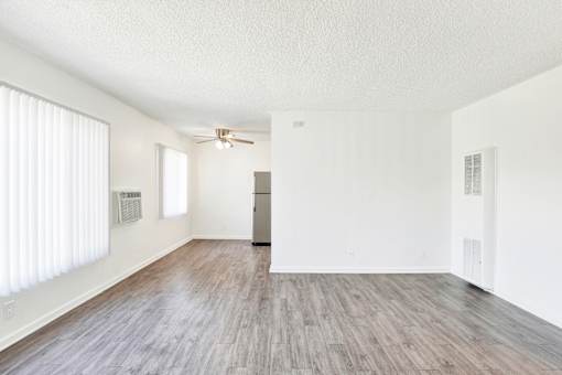 A spacious room with wooden flooring and a refrigerator in the corner at Sylvan Gardens,Van Nuys,91401