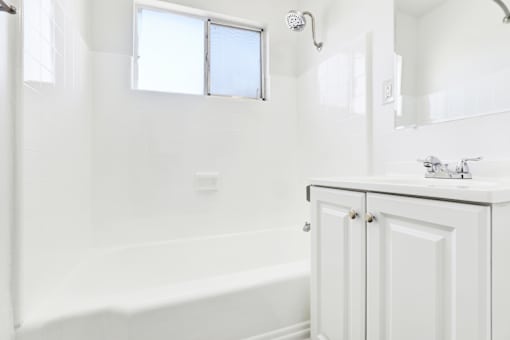 A white bathroom with a tub, sink, and mirror at Sylvan Gardens,California,91401
