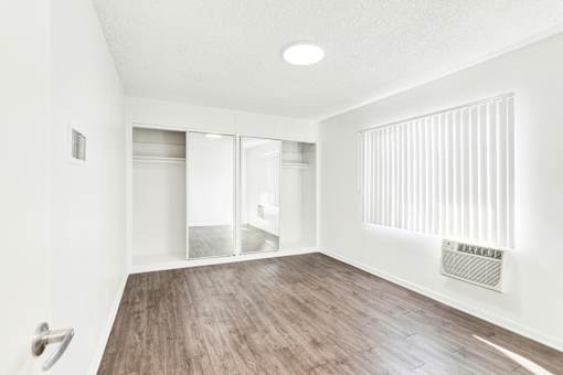 A room with a white wall and a wooden floor at Sylvan Gardens,Van Nuys,91401