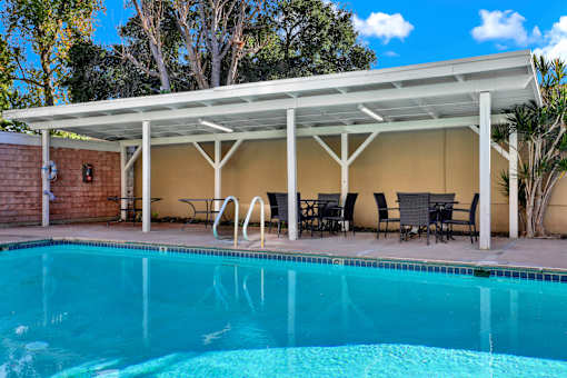 A pool under a white roof with chairs and tables around it at Sylvan Gardens,California,91401