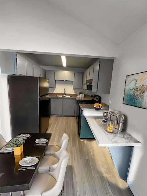 A modern kitchen with a black countertop and white chairs.