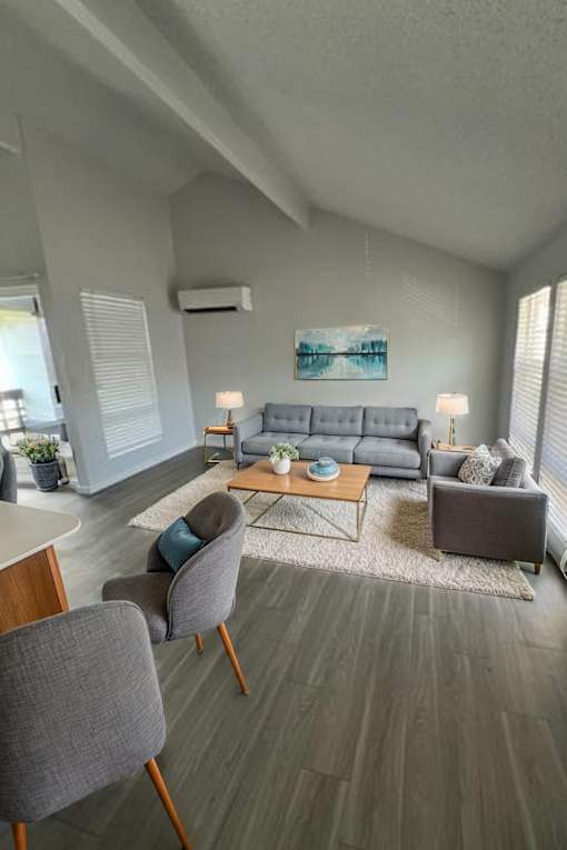 A living room with a grey couch, a grey chair, a wooden table, and a painting on the wall.