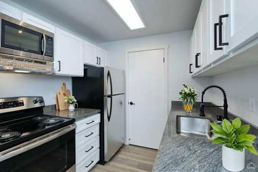 A kitchen with black appliances and white cabinets.
