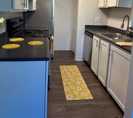 A kitchen with a black countertop and a blue cabinet.